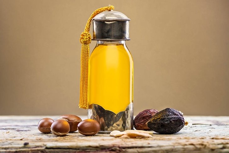 Bottle of argan oil and fruits for skin care